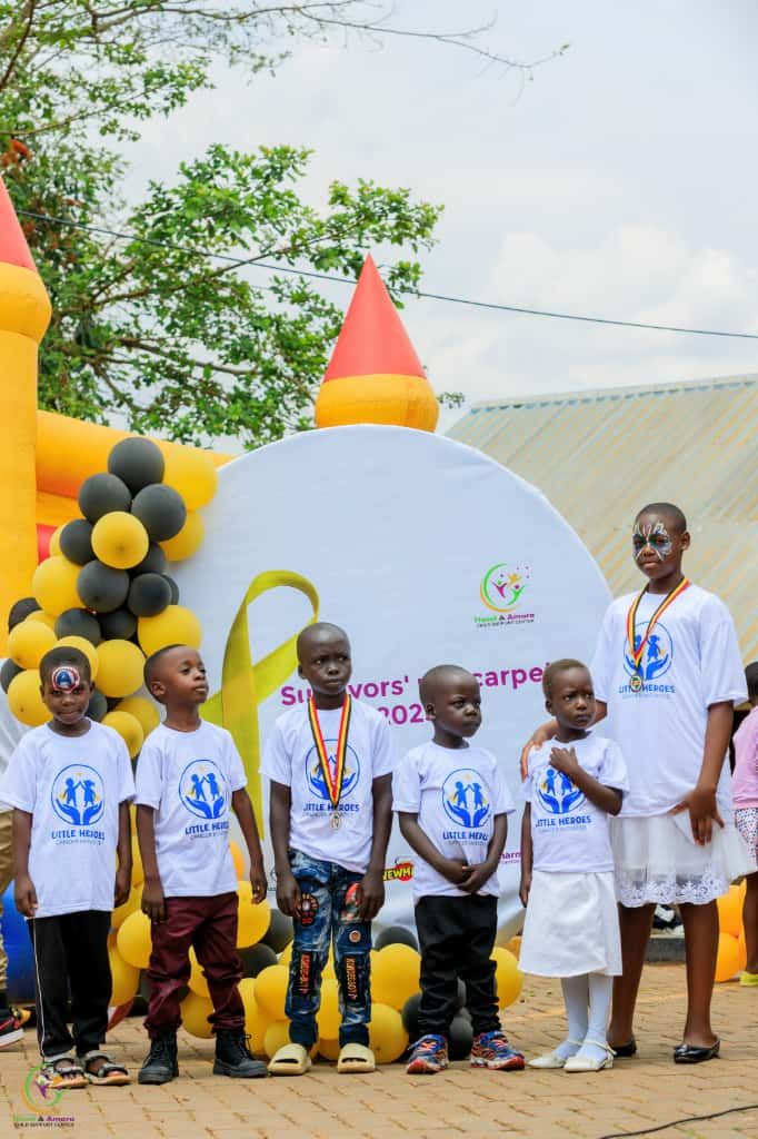 Children in Little Heroes t-shirts in front of balloons and a bouncy castle