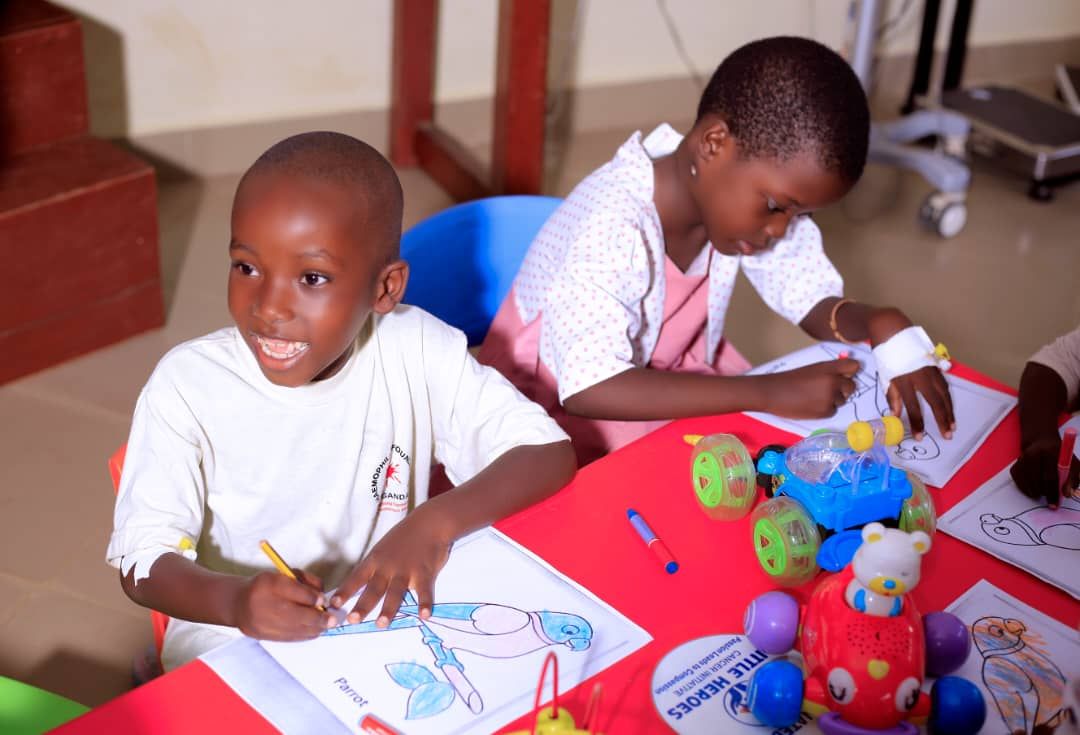 Two children colouring pictures at a red table