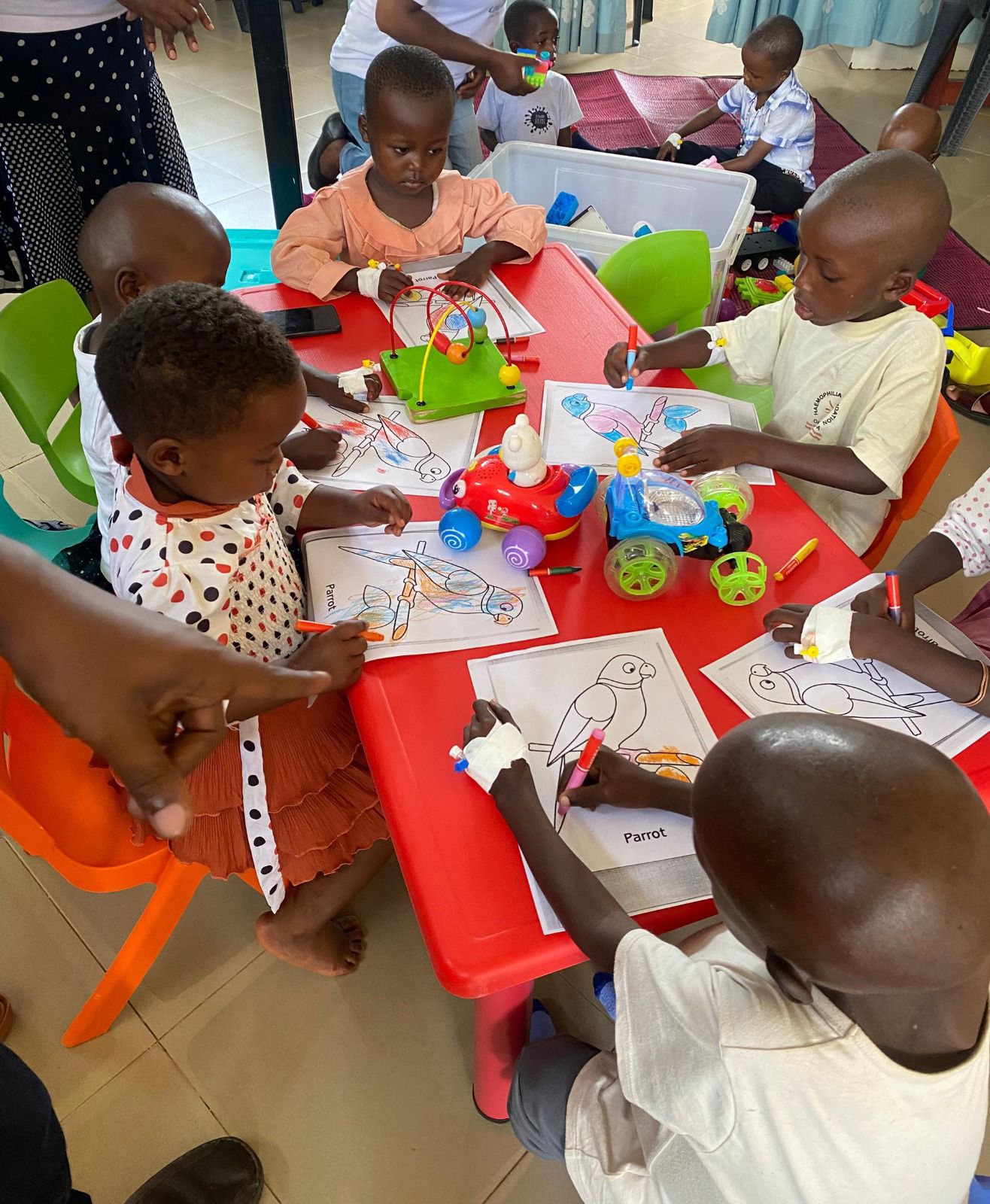Children drawing and playing with toys around a table
